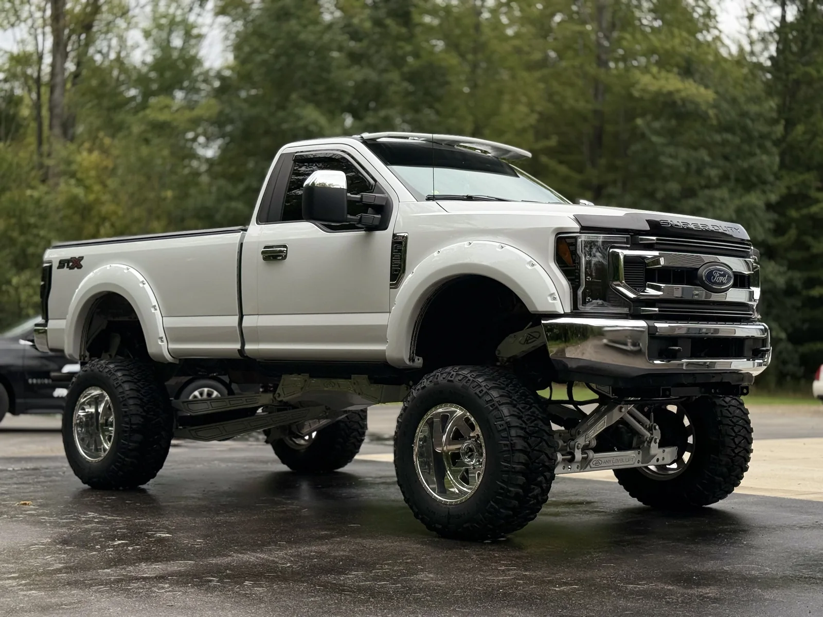 Lifted white Ford Super Duty STX pickup with polished wheels after detailing