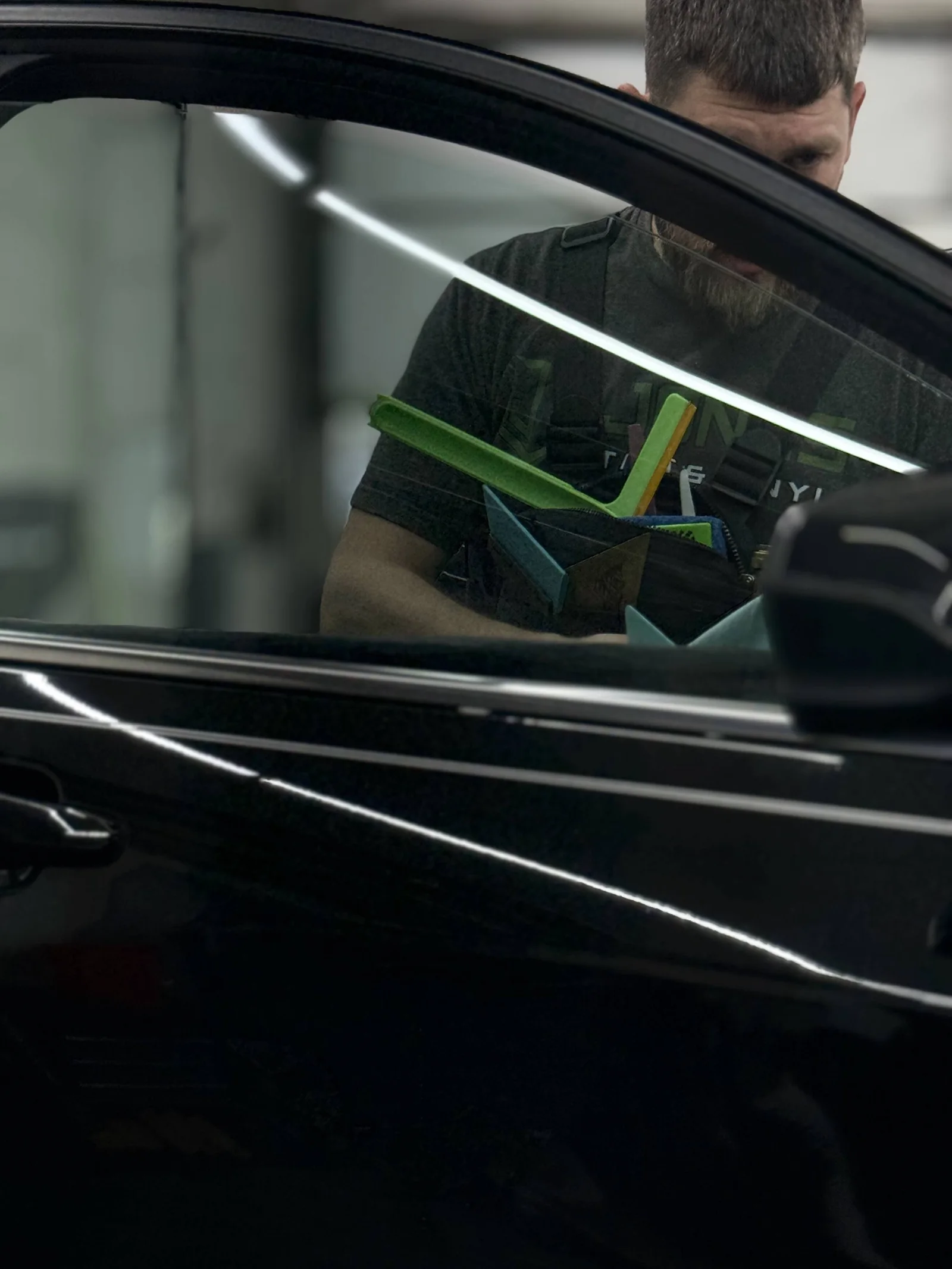 Window tint film being installed on a black car's door glass